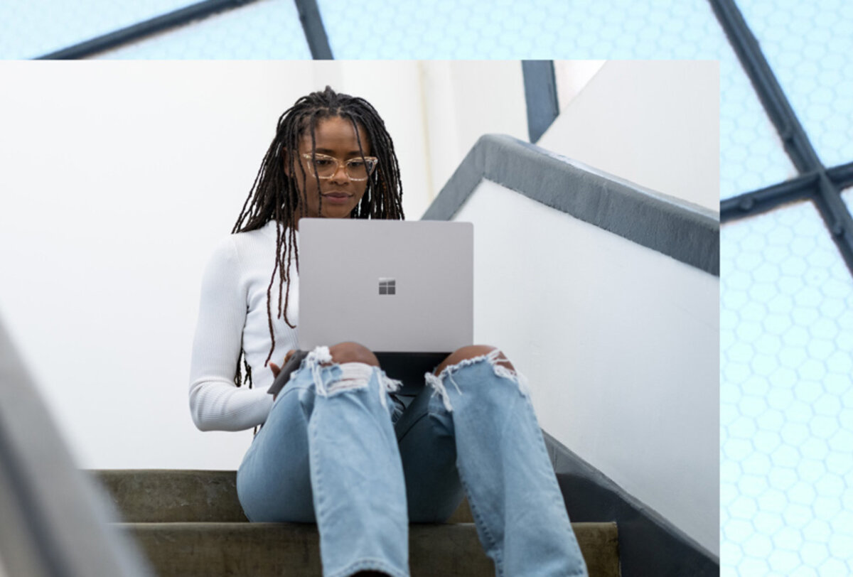 Laptop Microsoft Surface 5 15” platynowy grafika przedstawia kobietę siedzącą na schodach z laptopem na kolanach