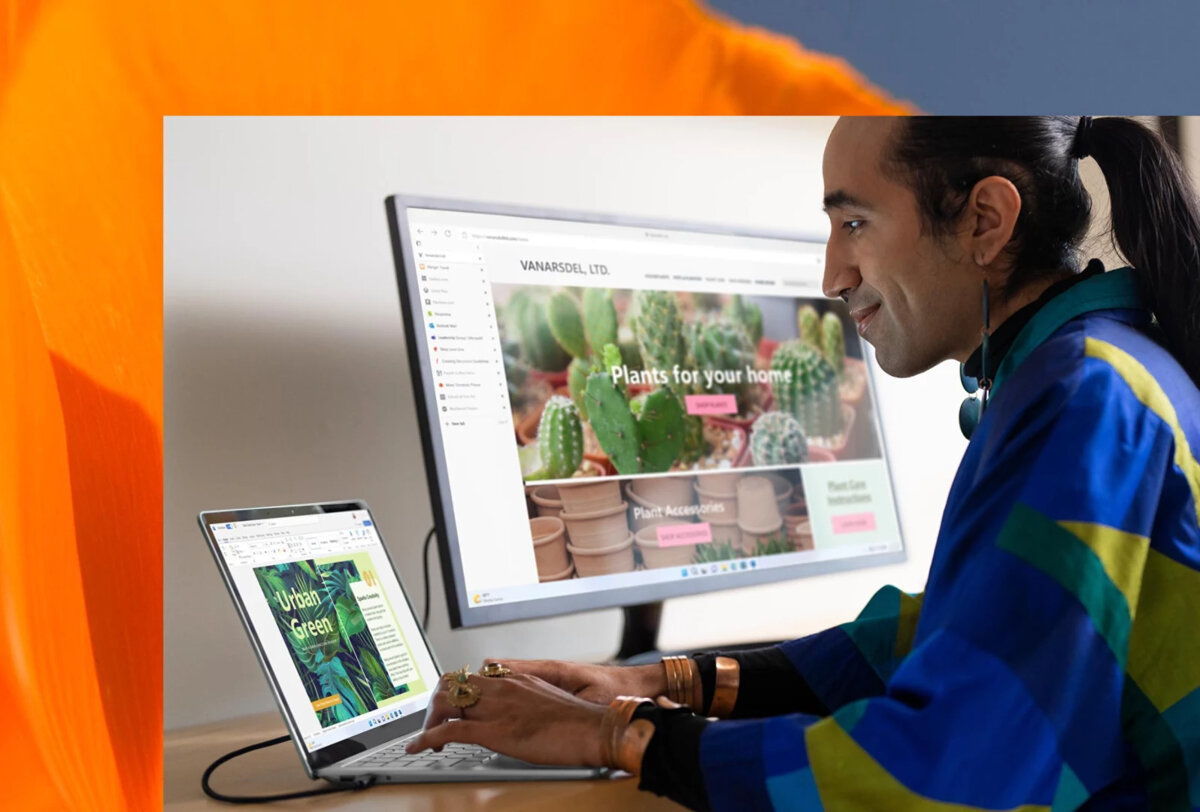 Laptop Microsoft Surface 5 15” platynowy grafika przedstawia mężczyznę piszącego na klawiaturze włączonego laptopa obok stoi włączony i podłączony do laptopa monitor