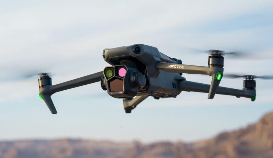 Dron DJI Mavic 3 Pro (DJI RC) 21 m/s pokazany dron unoszący się w powietrzu pod ukosem