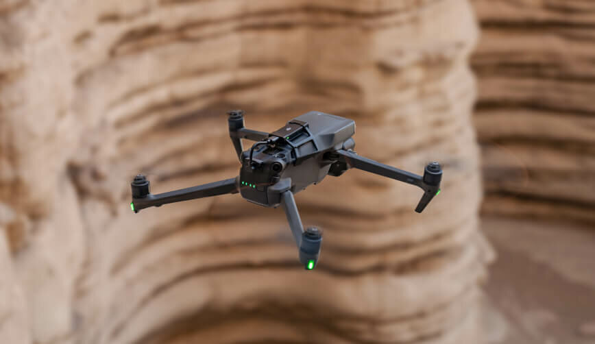 Dron DJI Mavic 3 Pro Cine Premium Combo widok na lecącego drona pod skosem w lewo na tle kanionu