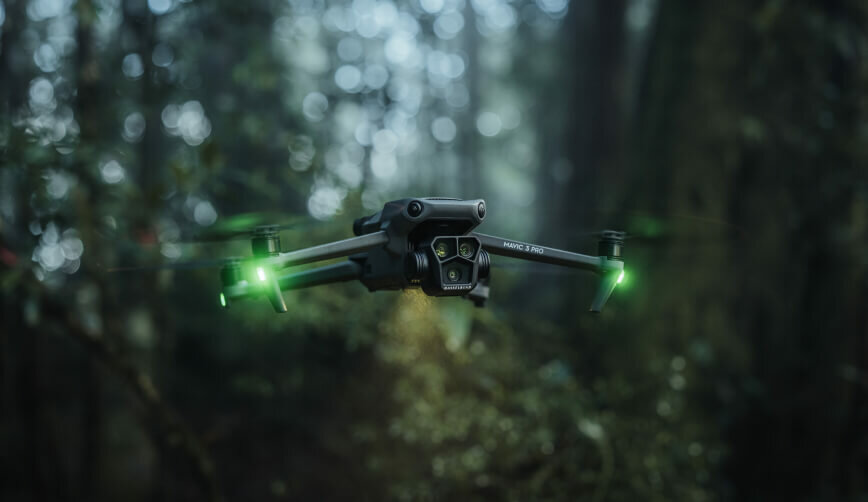 Dron DJI Mavic 3 Pro Cine Premium Combo widok na lecącego drona pod skosem w prawo w lesie