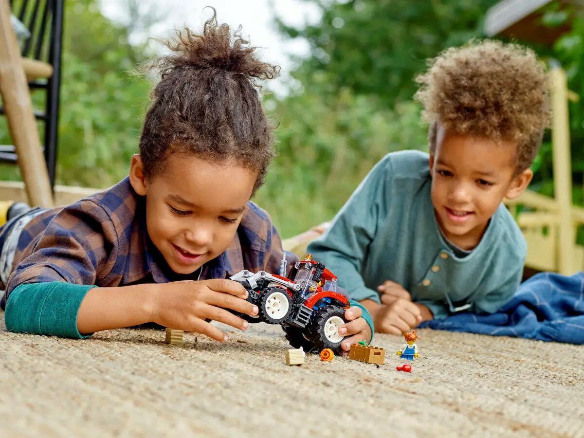 Klocki Lego City Traktor 60287 dzieci bawiące się klockami i traktorem na dywanie w pozycji leżącej