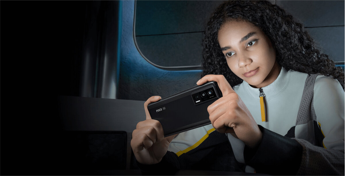 Smartfon Xiaomi POCO F5 Pro 12+256GB dziewczyna trzymająca włączony telefon w dłoniach w ciemnym pomieszczeniu