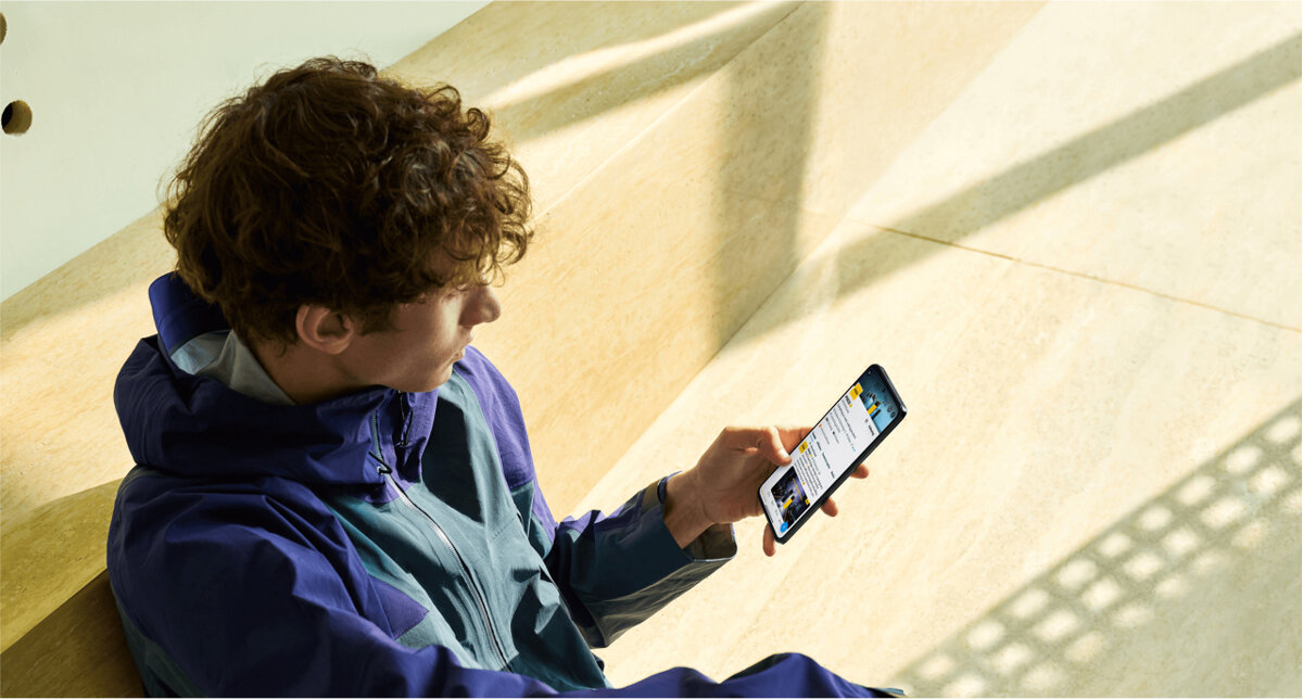 Smartfon Xiaomi POCO F5 Pro 12+256GB w ręku mężczyzny z włączonym wyświetlaczem, w tle jasne płytki