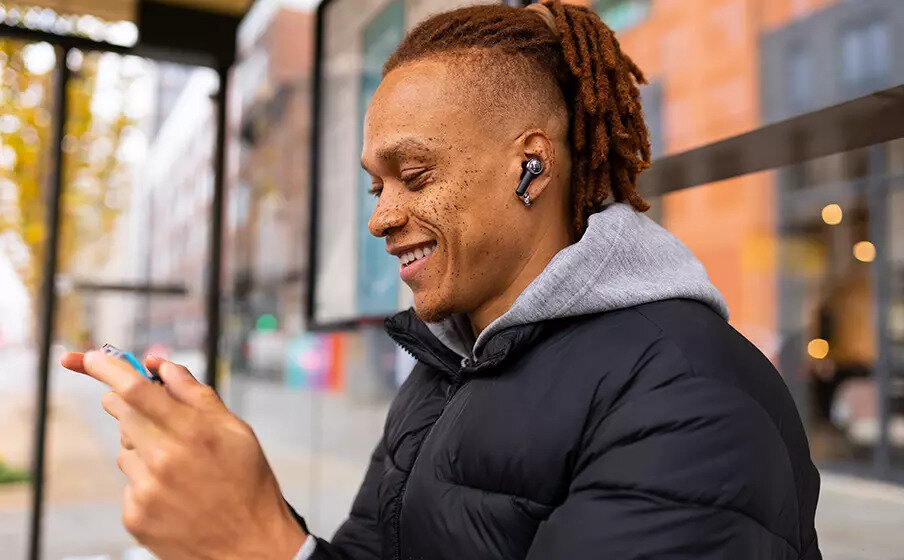Słuchawki douszne JBL Quantum TWS bluetooth czarne mężczyzna ze słuchawkami w uszach trzymający telefon w rękach