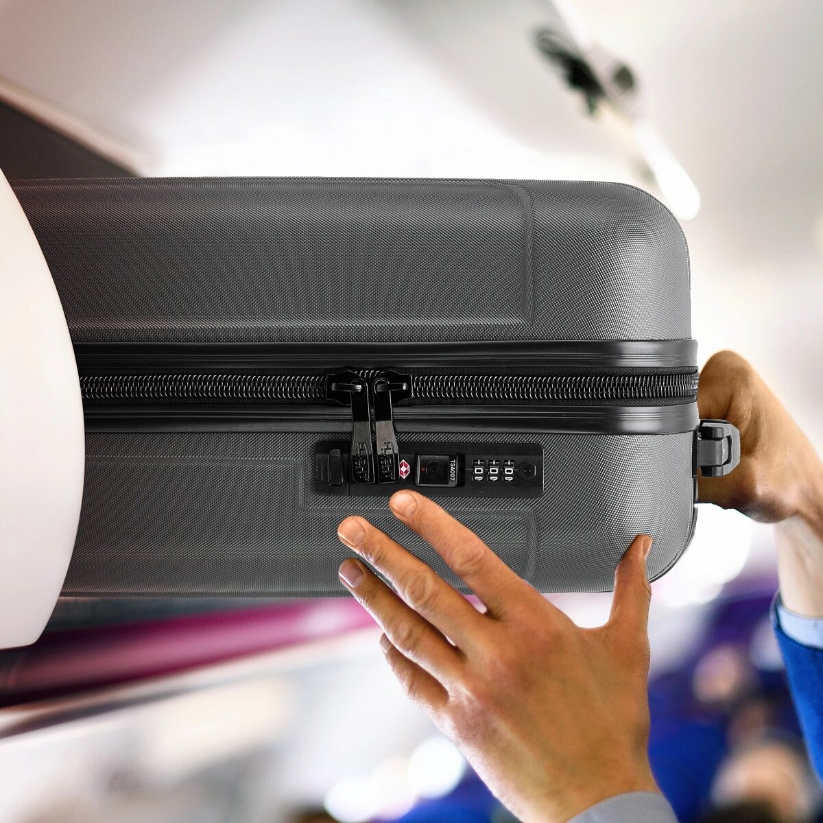 Walizka Anpa duża antracytowa  wkładanie  walizki w kabinie samolotu w miejsce na bagaże nad fotelem