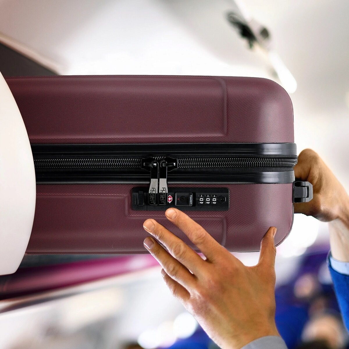 Walizka Anpa średnia granatowa  wkładanie  walizki w kabinie samolotu w miejsce na bagaże nad fotelem