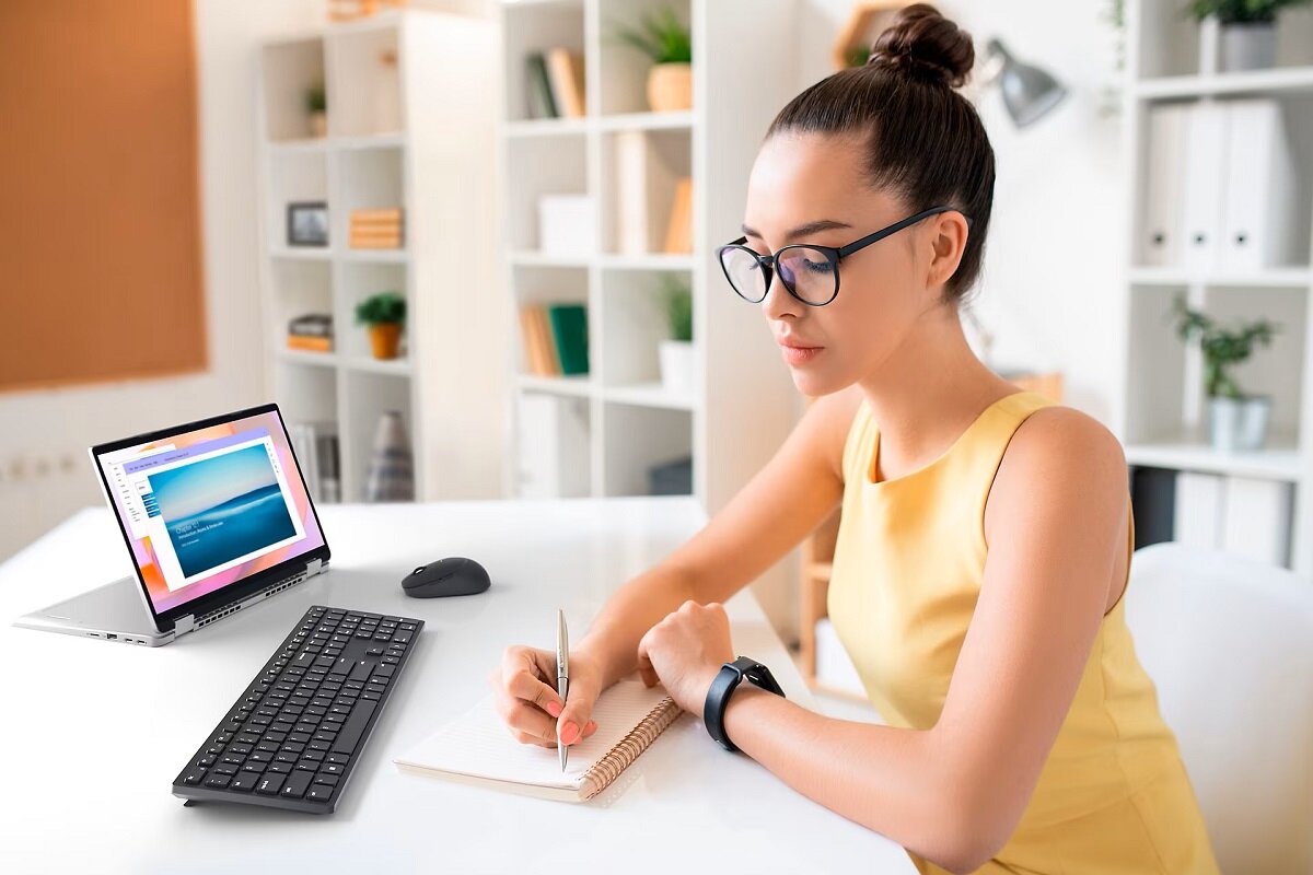 Klawiatura Dell KB500 US kobieta przy biurku z notesem, klawiaturą i laptopem 