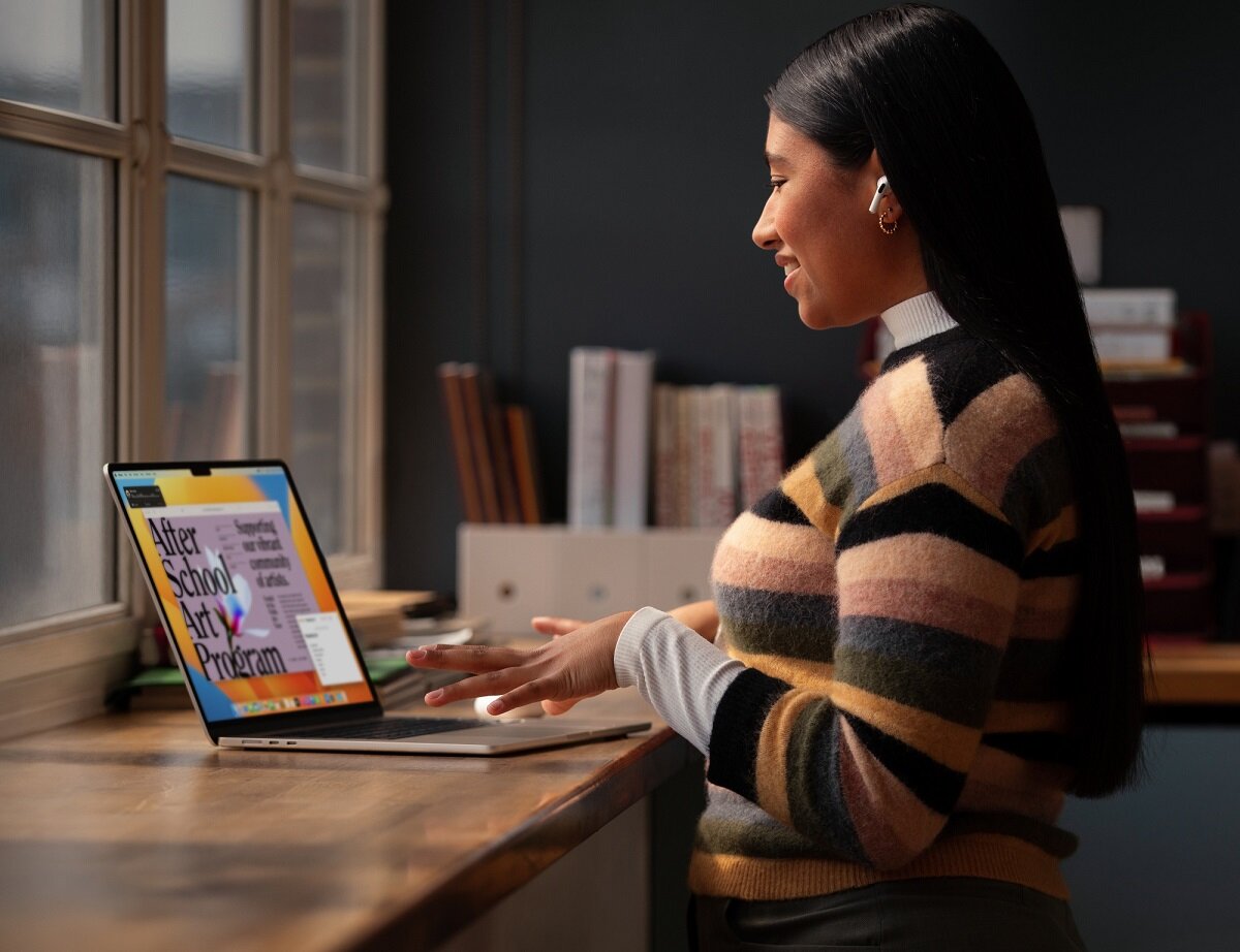Laptop Apple MacBook Air 2023 15.3 Retina M2 8/256GB Srebrny na stole obok stojącej kobiety
