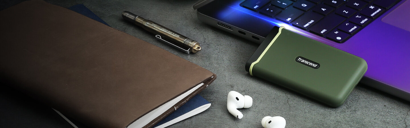 Dysk przenośny SSD Transcend ESD380C 4TB na biurku po skosie oparty o laptopa, słuchawki, długopis oraz notatniki