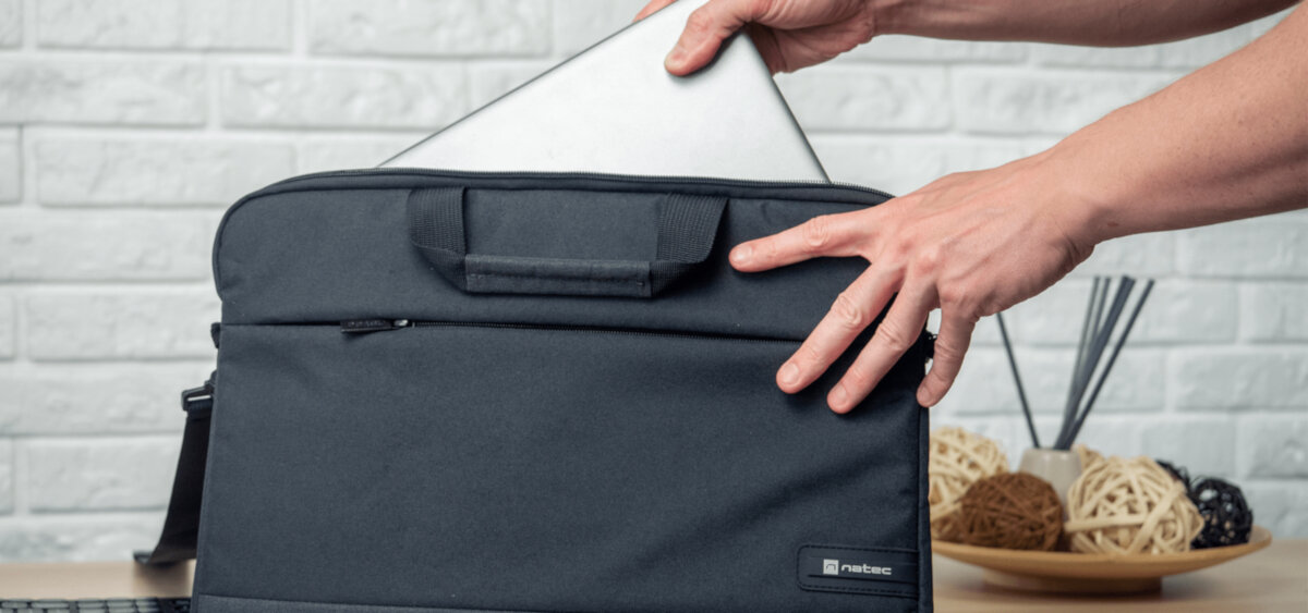 Torba na laptopa Natec Goa 15.6 czarna w rękach mężczyzny wkładającego laptop do torby