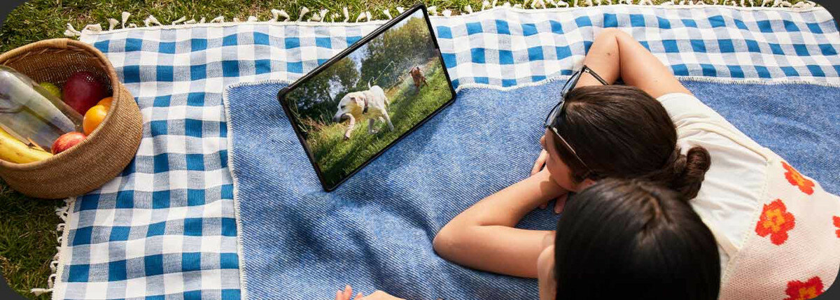 Tablet Samsung Galaxy Tab S9+ grafika przedstawiająca dwie dziewczyny na kocu oglądające film na tablecie