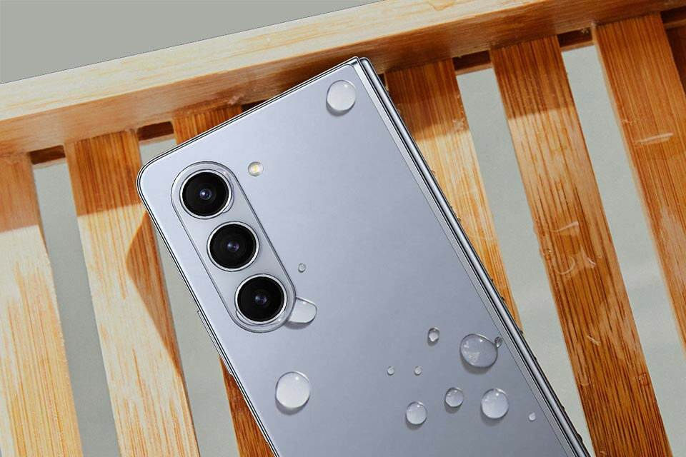 Smartfon Samsung Galaxy Z Fold5 położony na deskach od tyłu z kroplami wody na obudowie