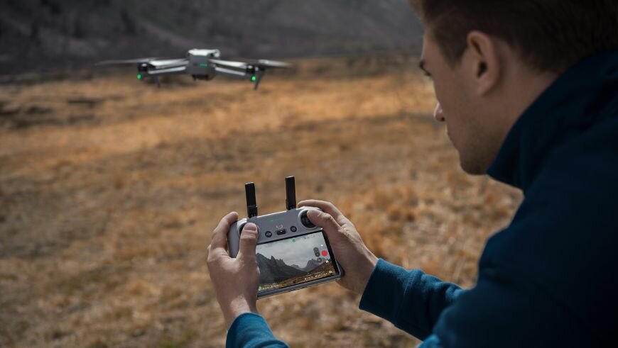Dron DJI Air 3 Fly More Combo (DJI RC 2) 6000m mężczyzna trzymający kontroler w dłoniach sterując dronem