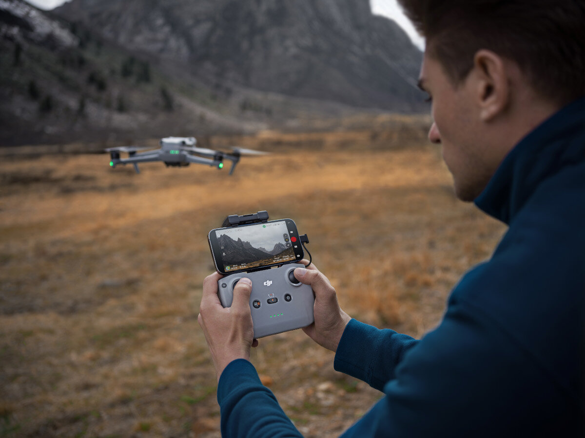 Dron DJI Air 3 Fly More Combo (DJI RC-N2) 6000m mężczyzna trzymający kontroler w dłoniach sterując dronem