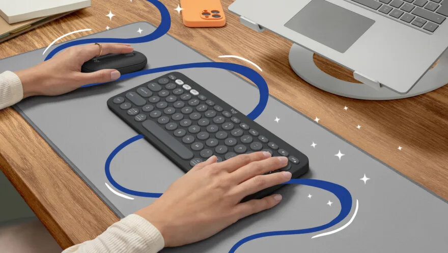Zestaw klawiatura i mysz Logitech Pebble 2 Combo różowy grafika przedstawia jedną rękę na klawiaturze i drugą na myszce obok smartfona oraz laptopa