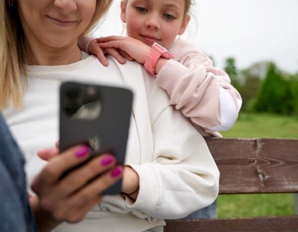 Smartwatch Garett Kids Sun Ultra 4G dziewczynka siedząca z mamą mająca smartwatch na nadgarstku