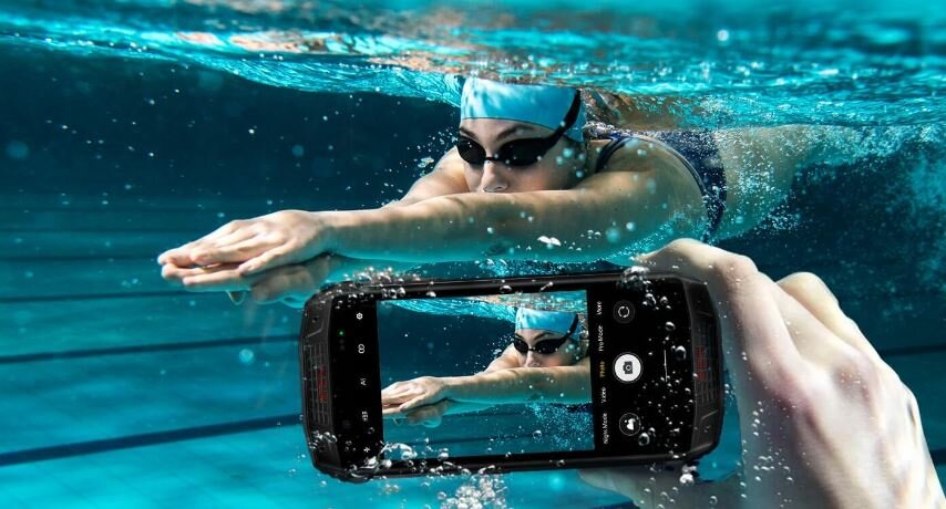Smartfon Ulefone Armor 15 grafika przedstawia smartfon pod wodą, którym robione jest zdjęcie płynącej kobiecie