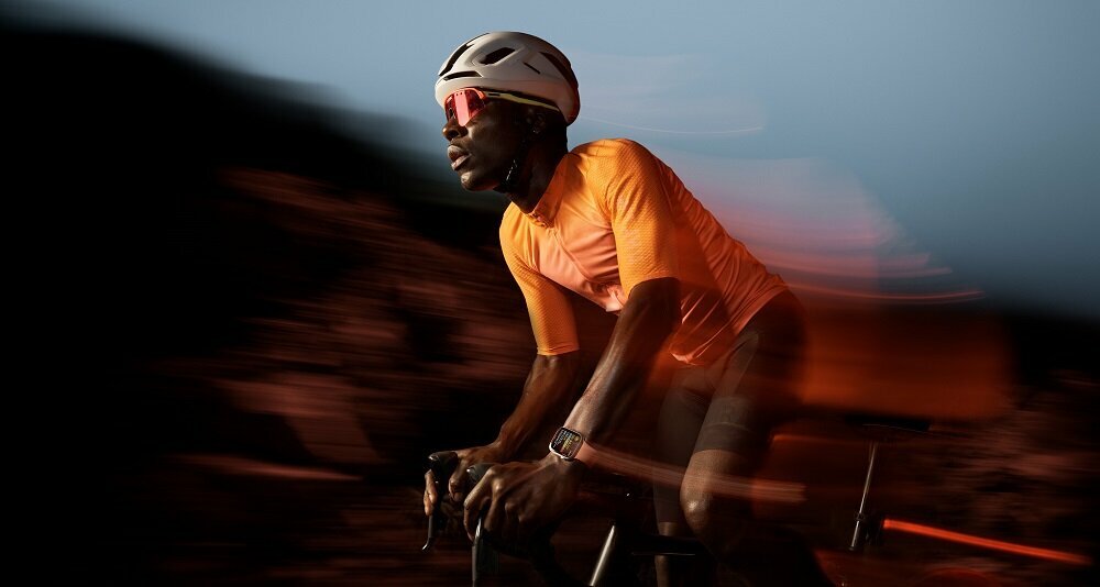 Smartwatch Apple Watch Series 9 GPS + Cellular aluminium 45mm różowy + opaska sportowa S/M jasnoróżowa widok na mężczyznę jadącego na rowerze ze smartwatchem na nadgarstku
