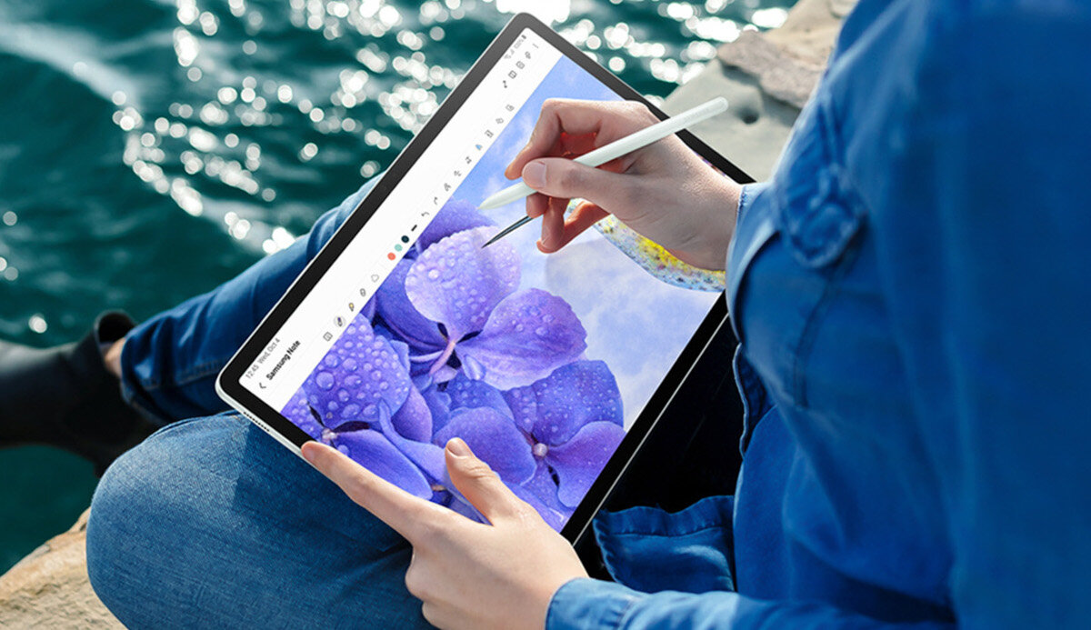Tablet Samsung Galaxy Tab S9 FE grafika przedstawiająca dziewczynę rysującą na tablecie nad wodą