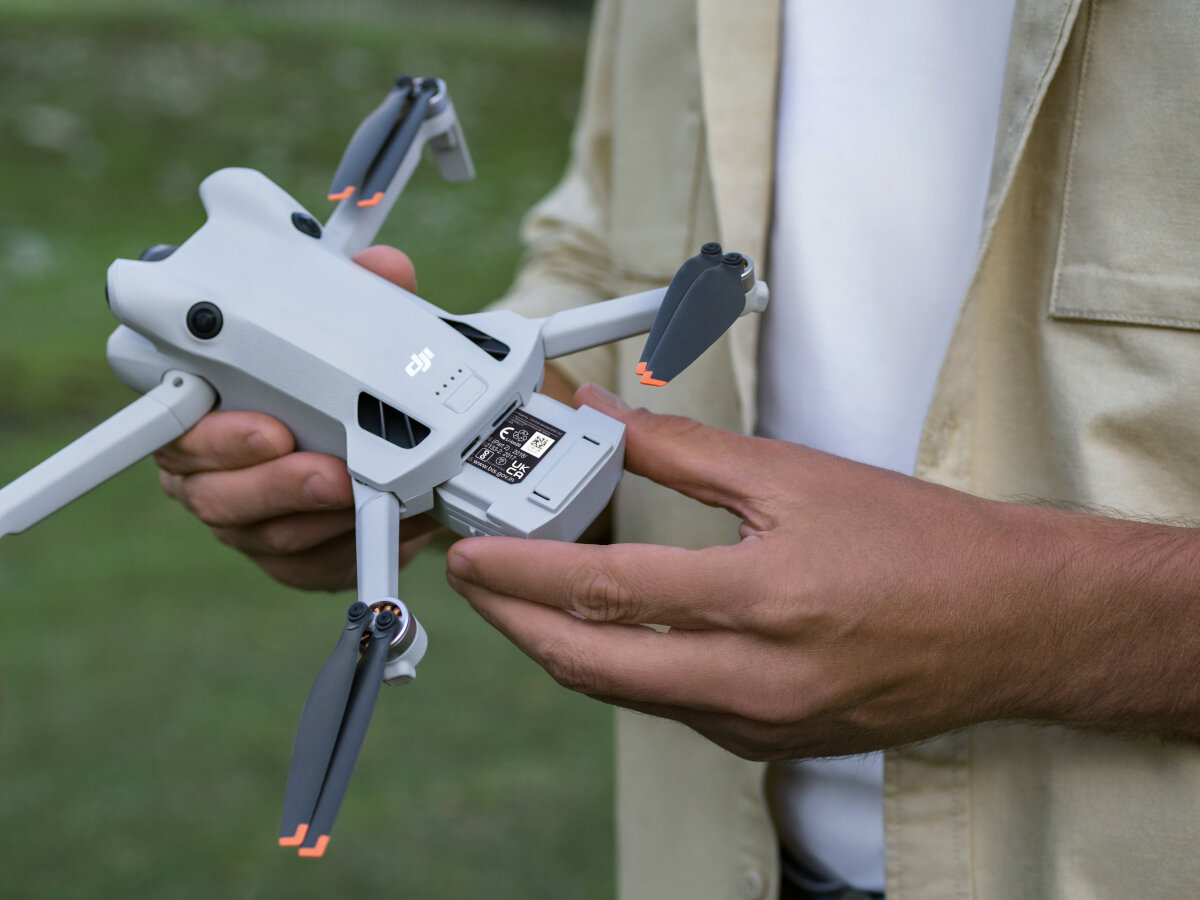 Dron DJI Mini 4 Pro Fly More Combo (DJI RC 2) grafika przedstawiająca mężczyznę trzymającego dron w rękach