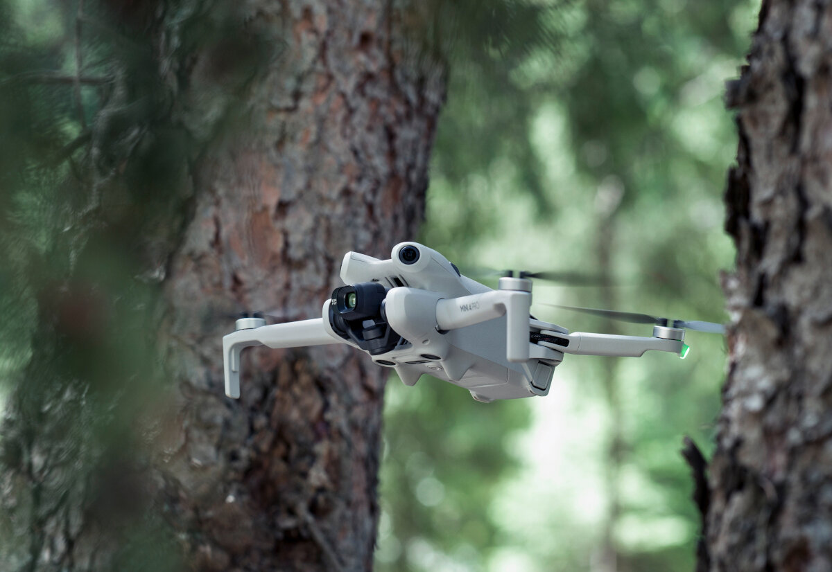 Dron DJI Mini 4 Pro (RC-N2) grafika przedstawiająca mężczyznę sterującego dronem przez kontroler nad potokiem
