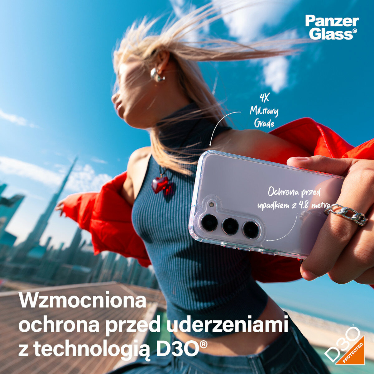 Etui PanzerGlass HardCase D3O Samsung Galaxy S24+ przezroczyste widok na kobietę trzymającą telefon z założonym etui na tle wieżowców 