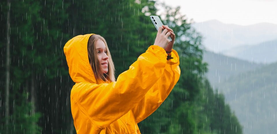 Smartfon Samsung Galaxy A55 5G 8/128GB błękitny widok na kobietę stojącą w deszczu w trakcie robienia zdjęcia smartfonem