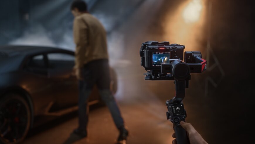 Stabilizator obrazu DJI RS 4 Pro Combo czarny widok na stabilizator trzmany w dłoni z zamontowaną kamerą w trakcie nagrywania mężczyzny wsiadającego do samochodu