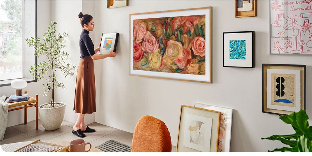 Telewizor Samsung QE75LS03DAUXXH 75” czarny grafika przedstawia kobietę wieszającą obrazek na ścianie obok telewizora w pokoju