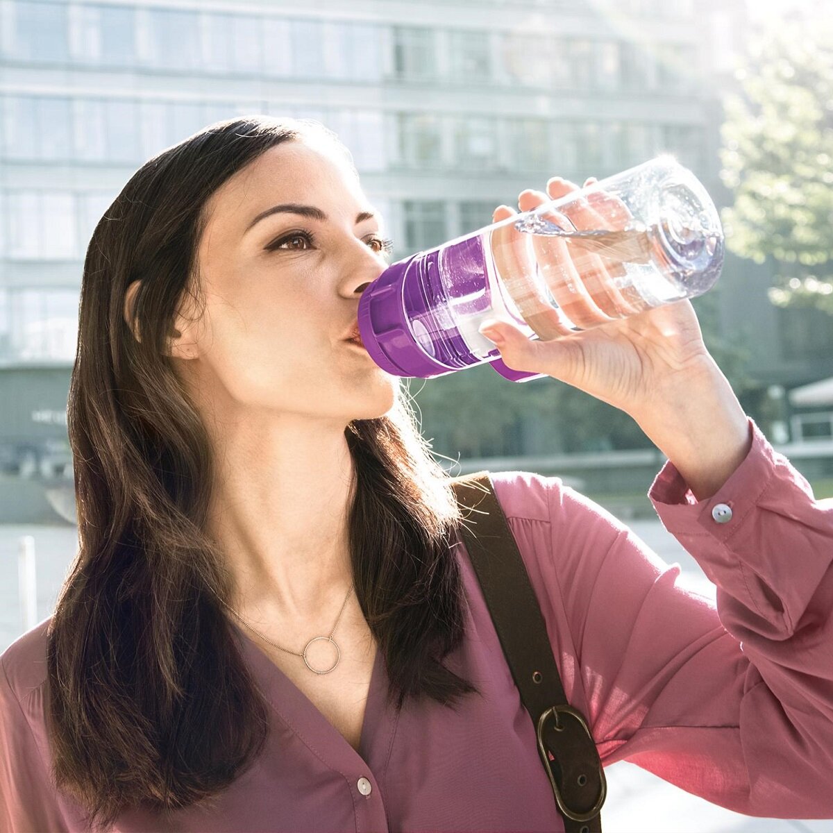 Butelka filtrująca Brita Fill&Go kobieta pije z butelki na tle miasta